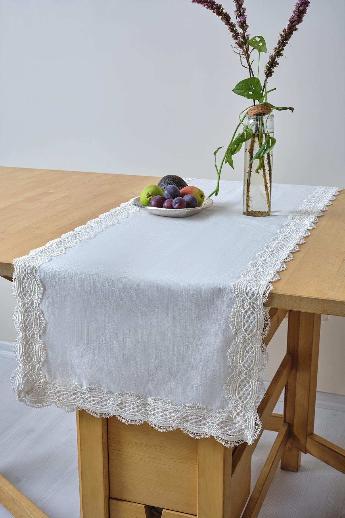 Runner da tavola bianco con dettagli in pizzo, con piatto di frutta e vaso in vetro su un tavolo in legno