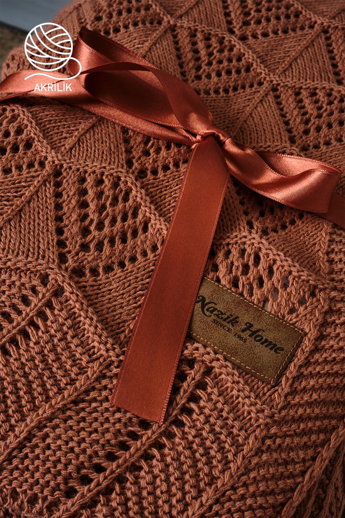 Coperta TV in acrilico a maglia grossa marrone, confezionata con nastro, con texture decorativa.