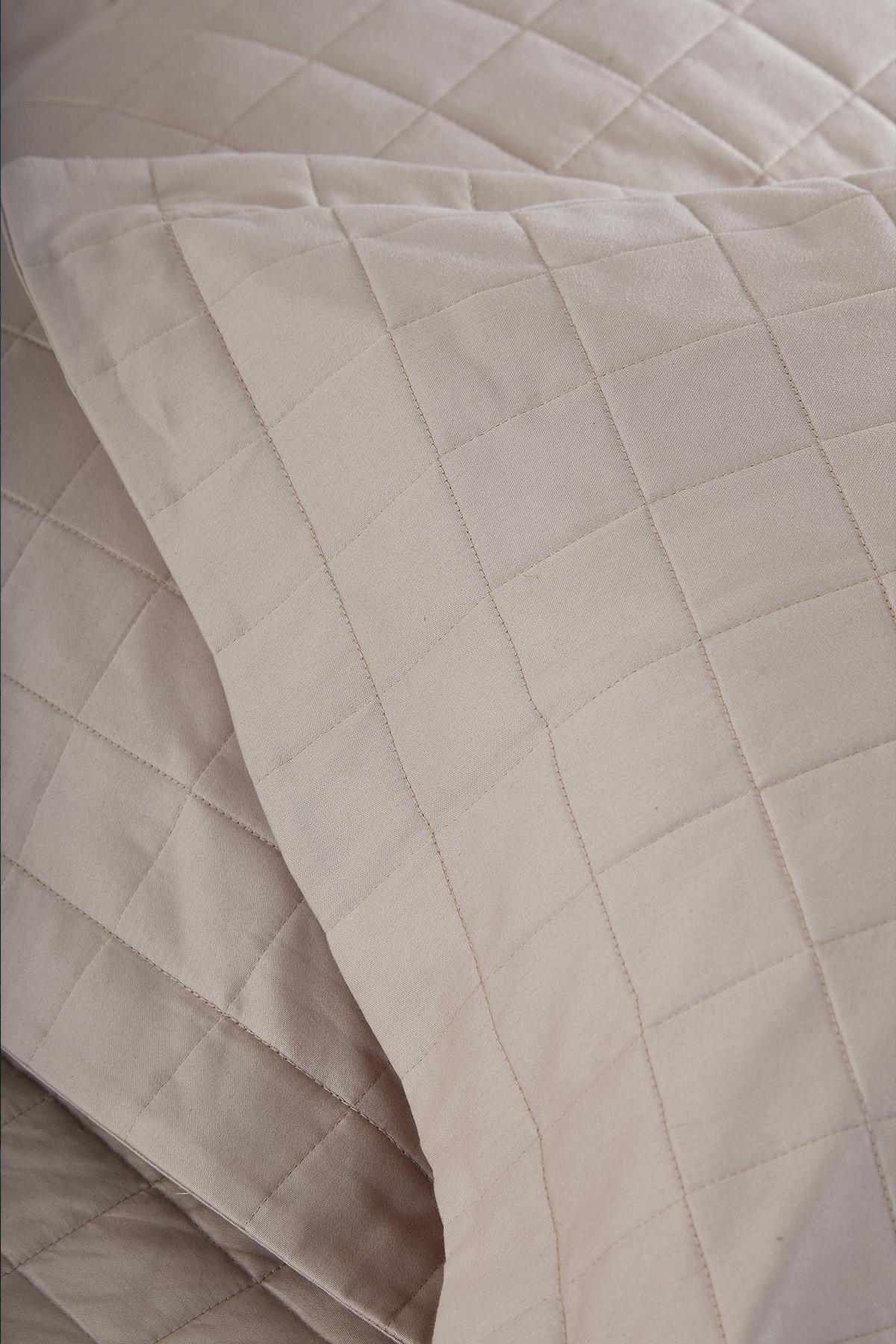 Primo piano di copriletto matrimoniale trapuntato beige con federa