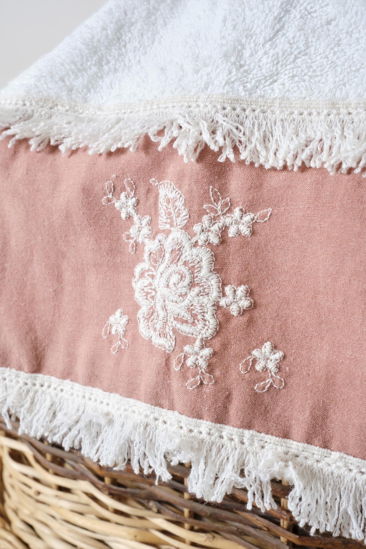 Primo piano di un asciugamano da bagno rosa e bianco con ricami in pizzo e nappe