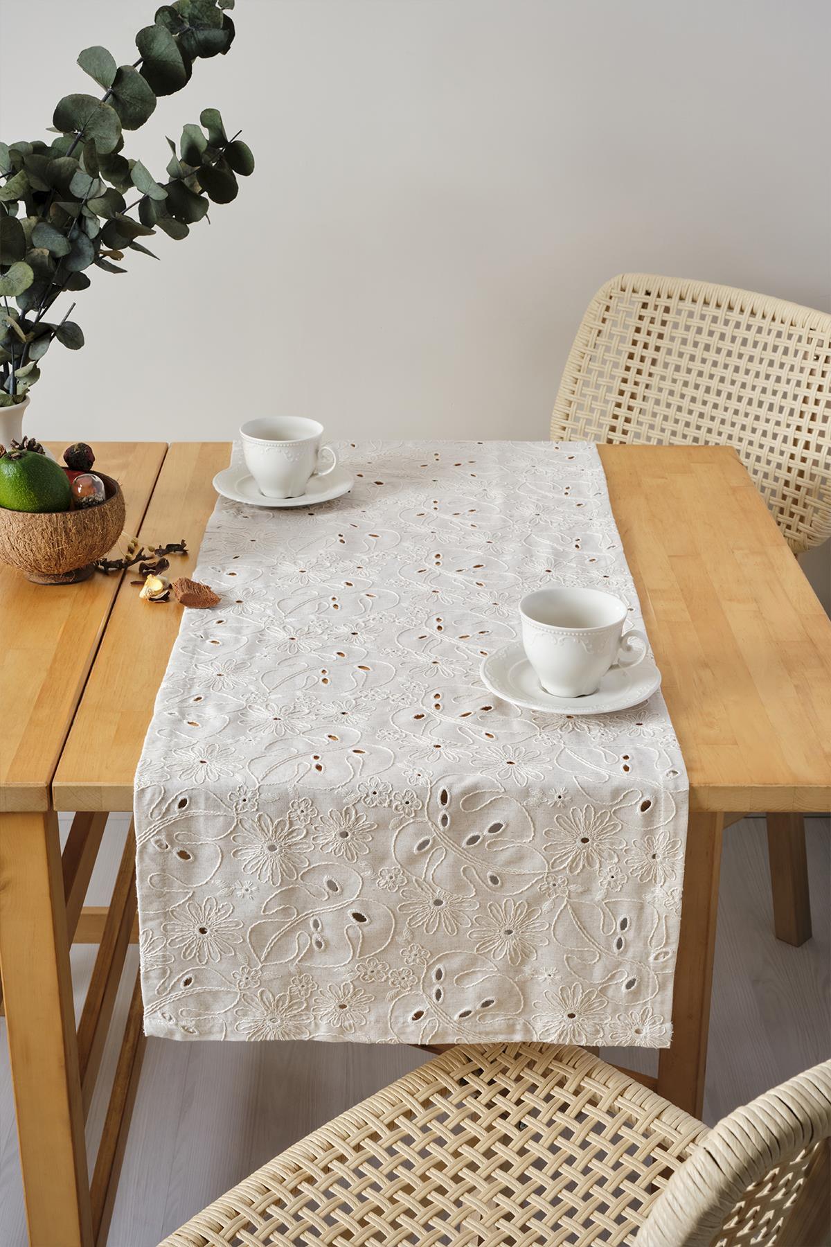 Runner da tavola color crema con ricami in pizzo, presentazione decorativa con due tazze su un tavolo in legno