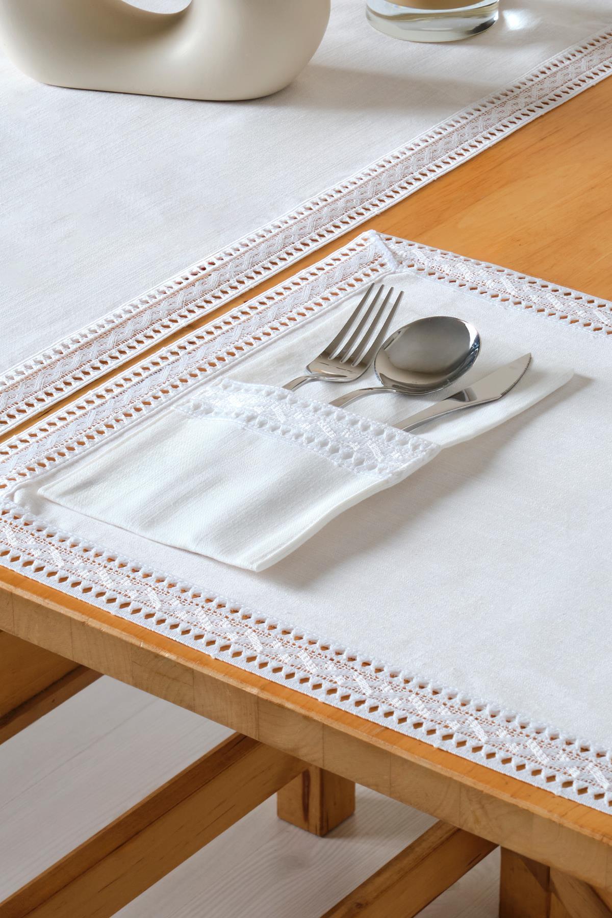 Elegante decorazione della tavola con tovaglia bianca in pizzo e set di posate composto da forchetta, coltello e cucchiaio in una tasca.