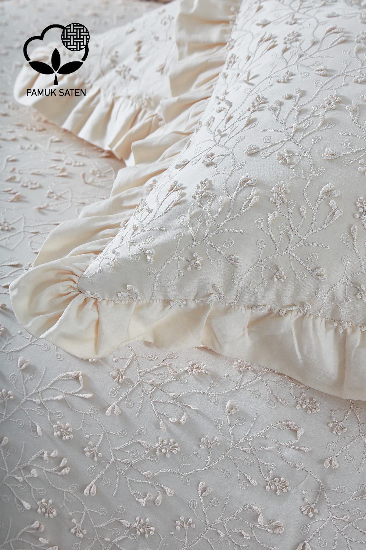 Set copripiumino matrimoniale in raso di cotone color crema con ricami, motivo floreale e federe con volant.