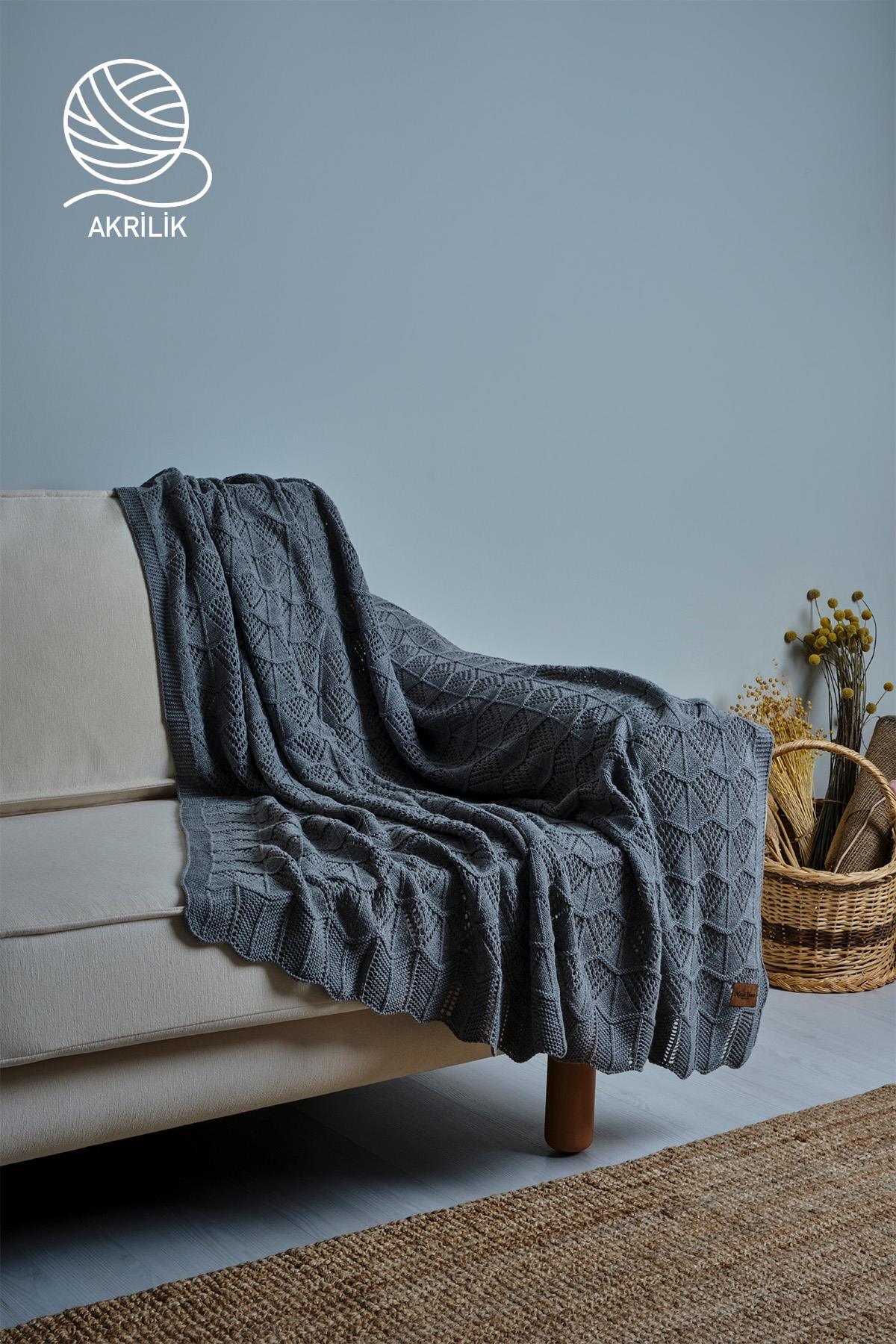 Coperta TV in maglia spessa acrilica grigia, stesa sul divano, in un arredamento da soggiorno.