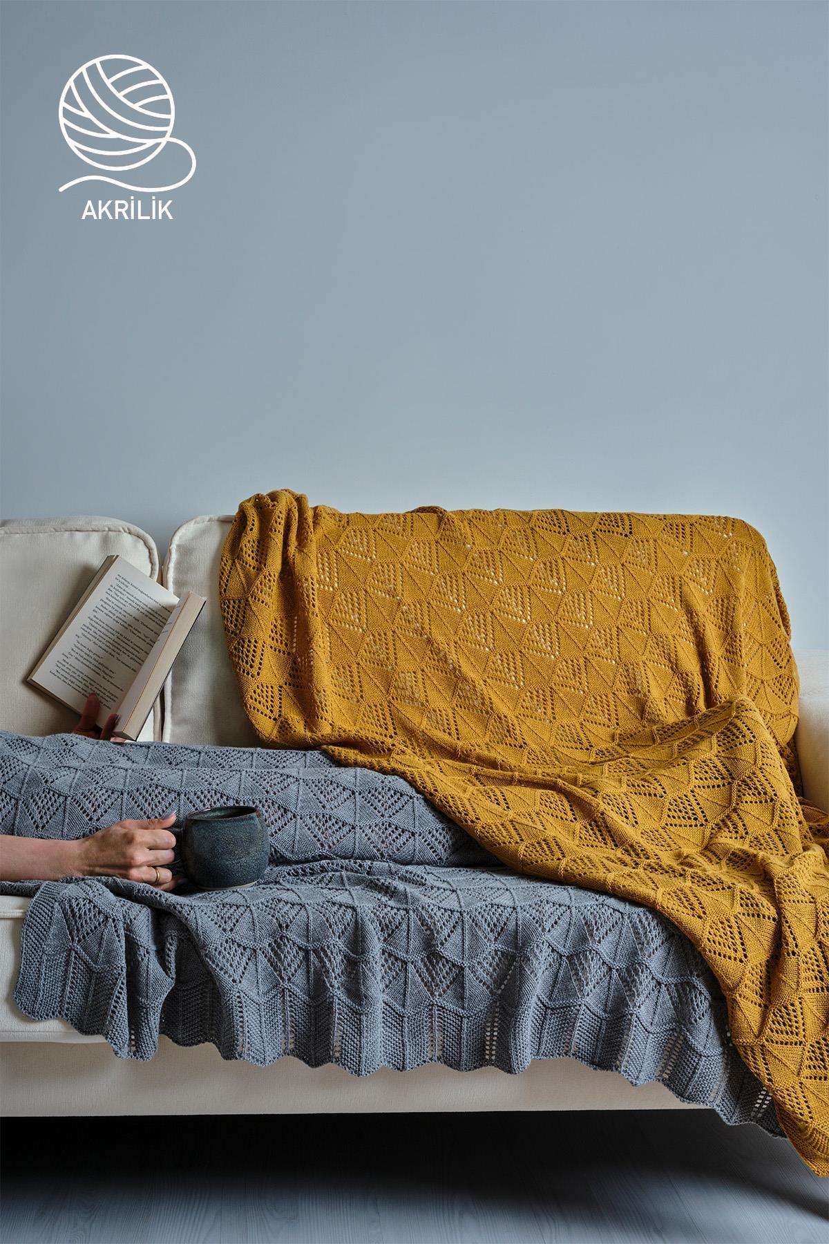 Coperta TV in maglia acrilica con motivo nei colori giallo e grigio, stesa sul divano.