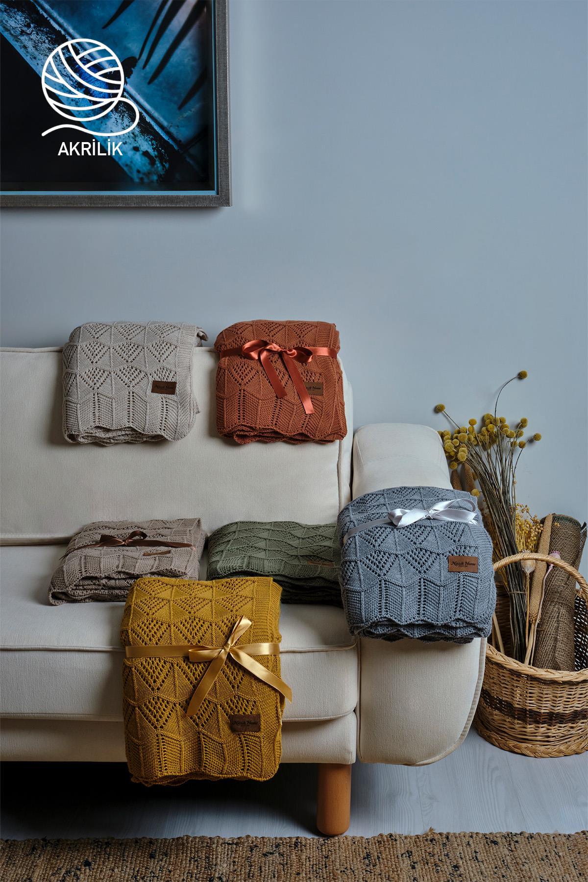 Coperte da TV in maglia grossa acrilica di vari colori disposte in modo decorativo su un divano.