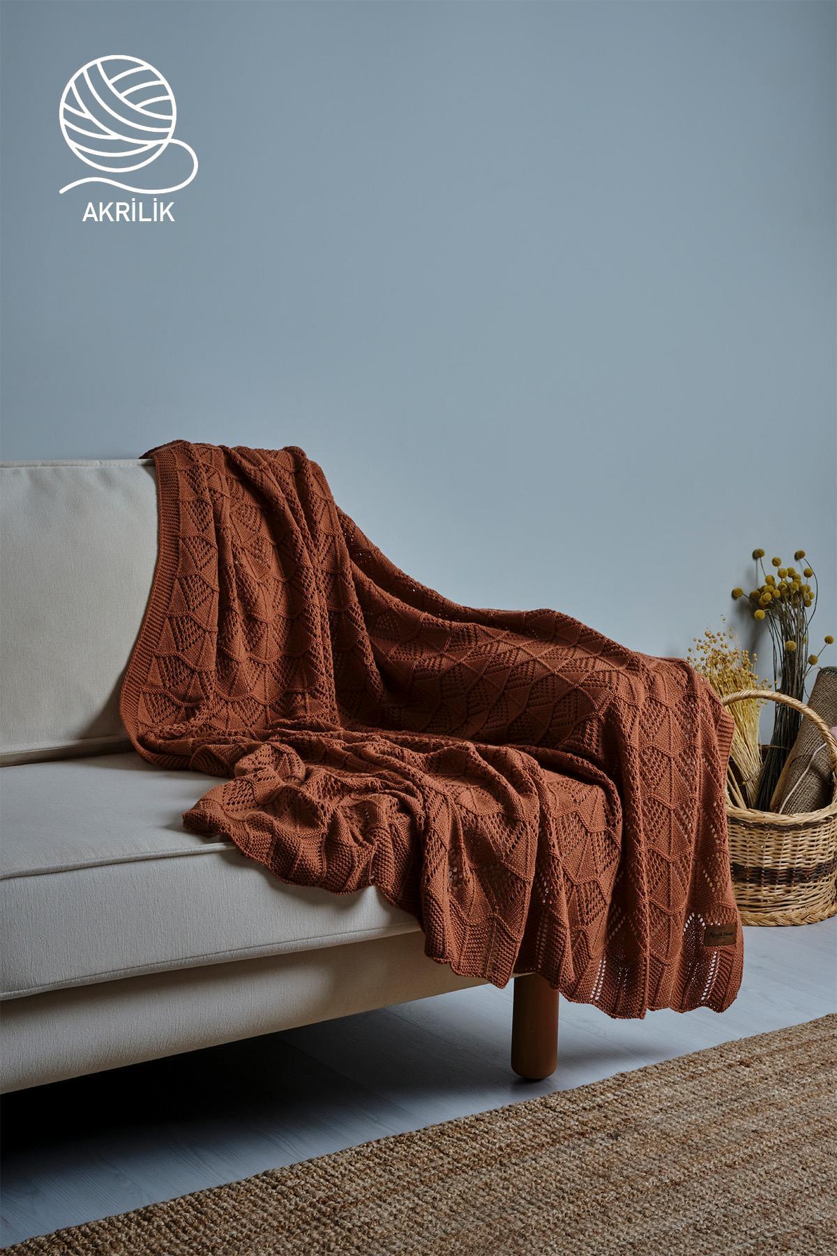 Coperta da TV in acrilico a maglia grossa marrone, su divano color crema e cesto decorativo
