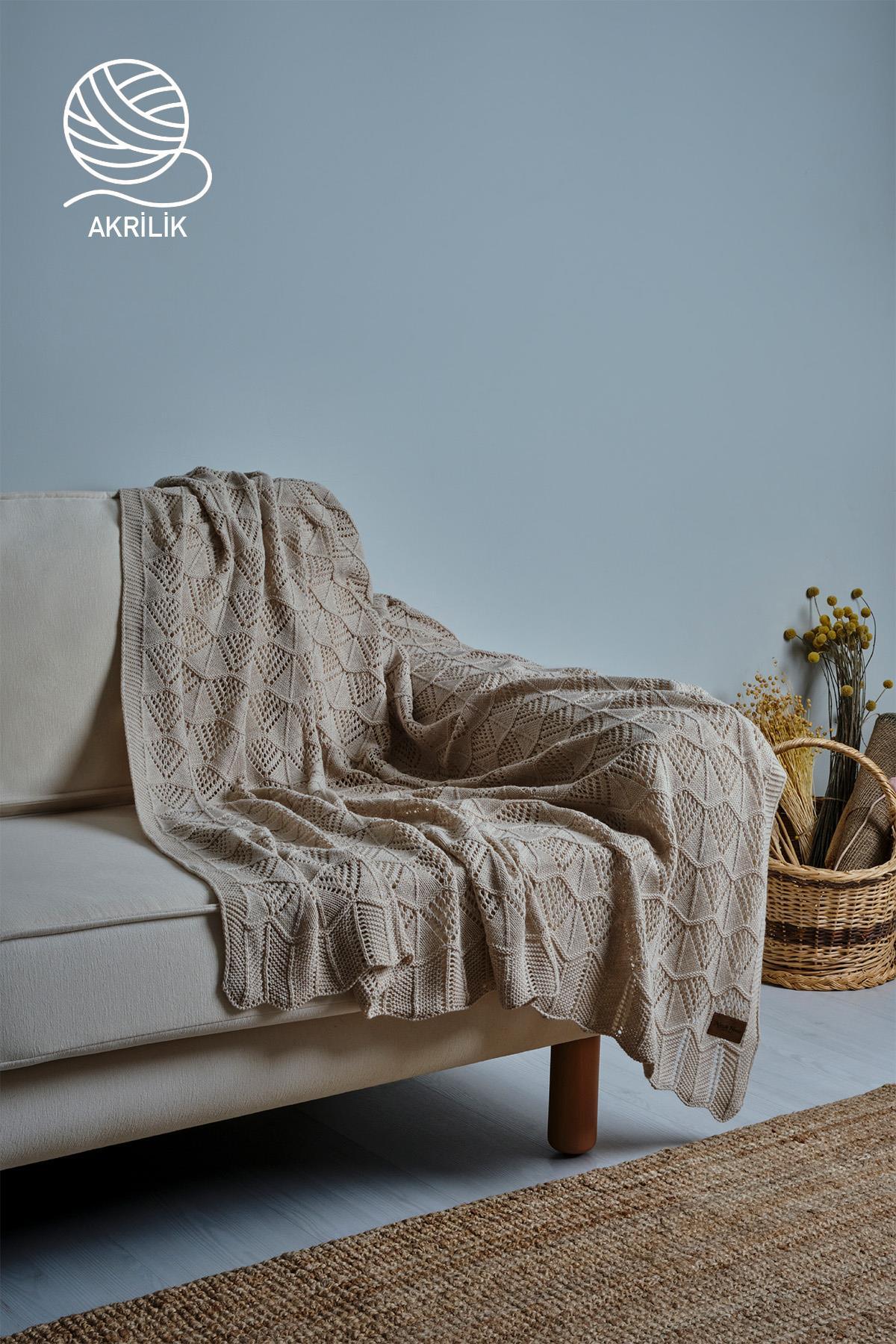 Coperta TV in maglia acrilica color crema, stesa su un divano, in una stanza dall'arredamento moderno
