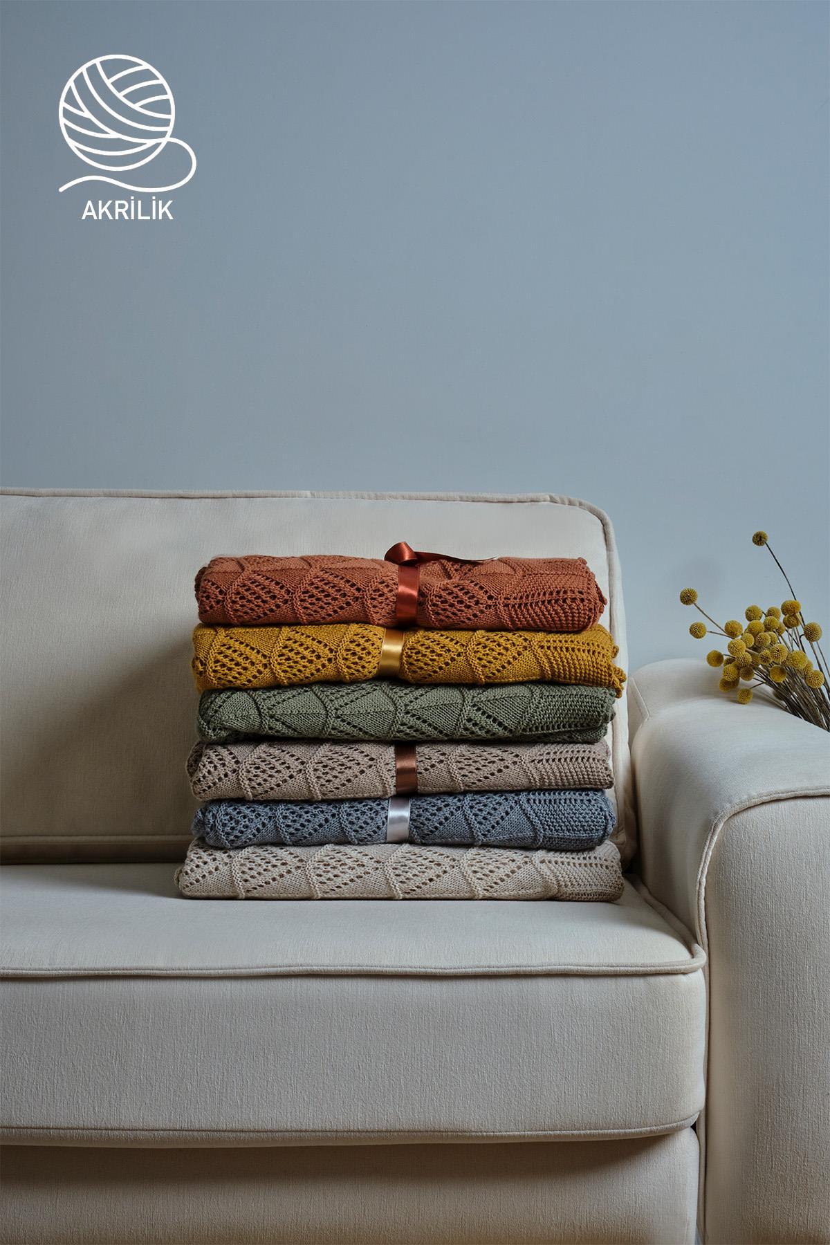 Coperte in maglia acrilica impilate su una poltrona, in diversi colori, decorazione moderna