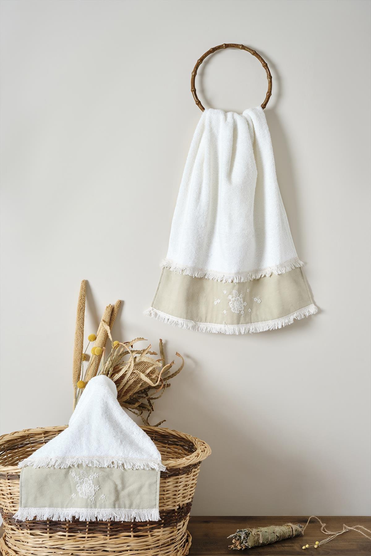 Asciugamano in cotone color crema con dettagli in pizzo, presentato con un cestino e fiori secchi decorativi.