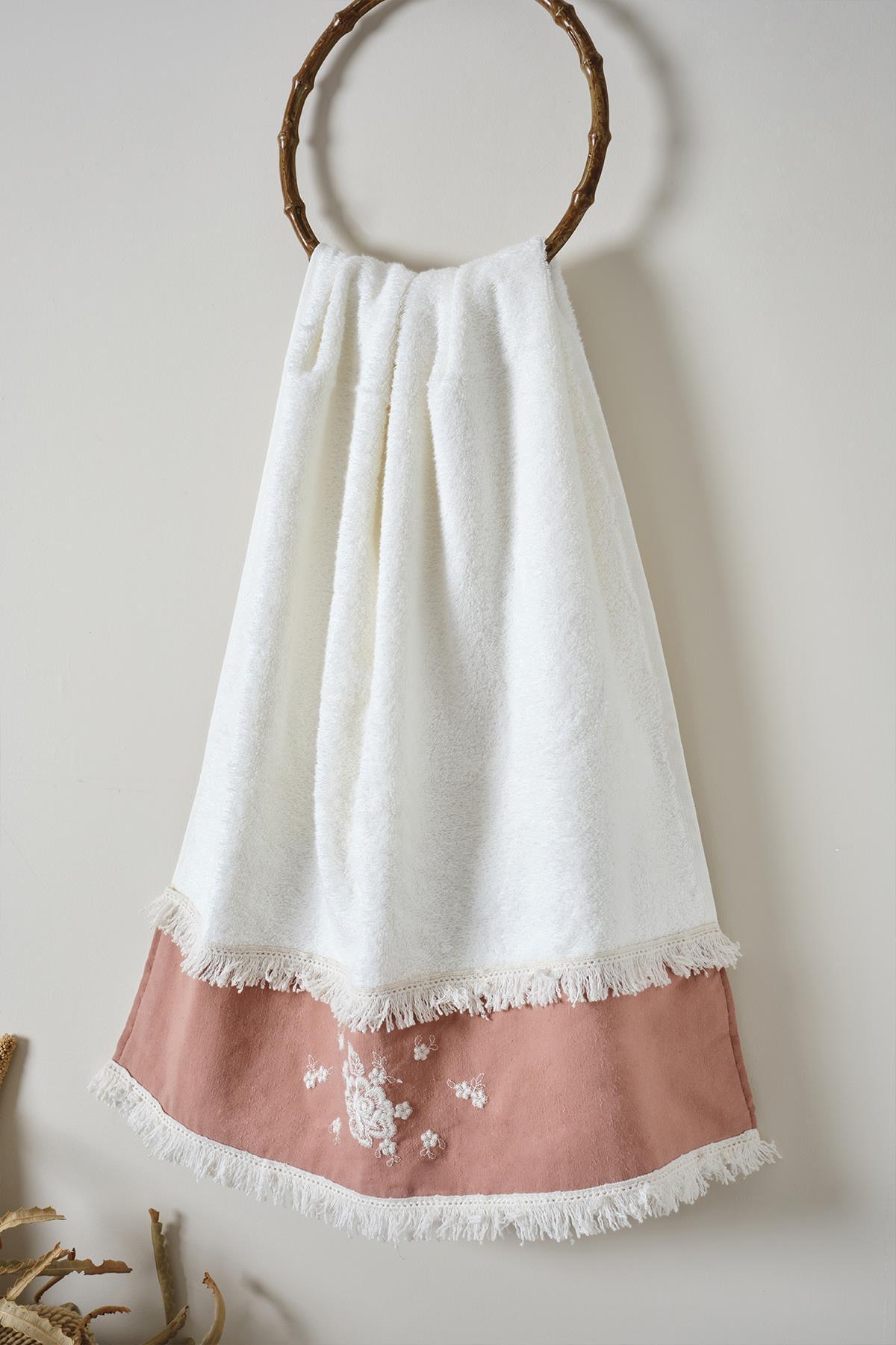 Asciugamano da bagno bianco con ricami in pizzo rosa e nappe, appeso a un gancio