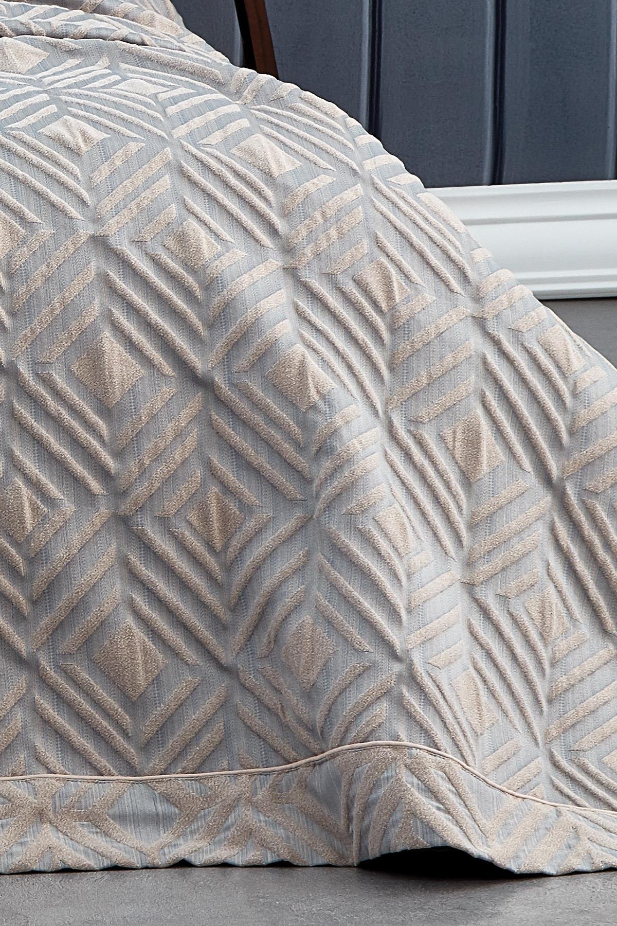 Dettaglio di copriletto matrimoniale jacquard con motivo geometrico grigio e beige