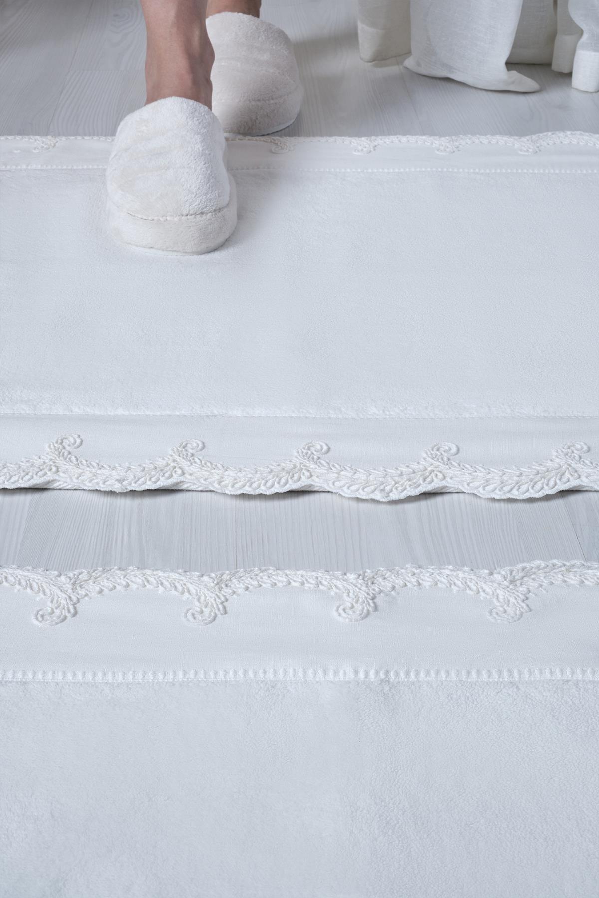 Set di 2 tappetini da bagno bianchi ricamati, con dettagli in pizzo sui bordi, su pavimento moderno