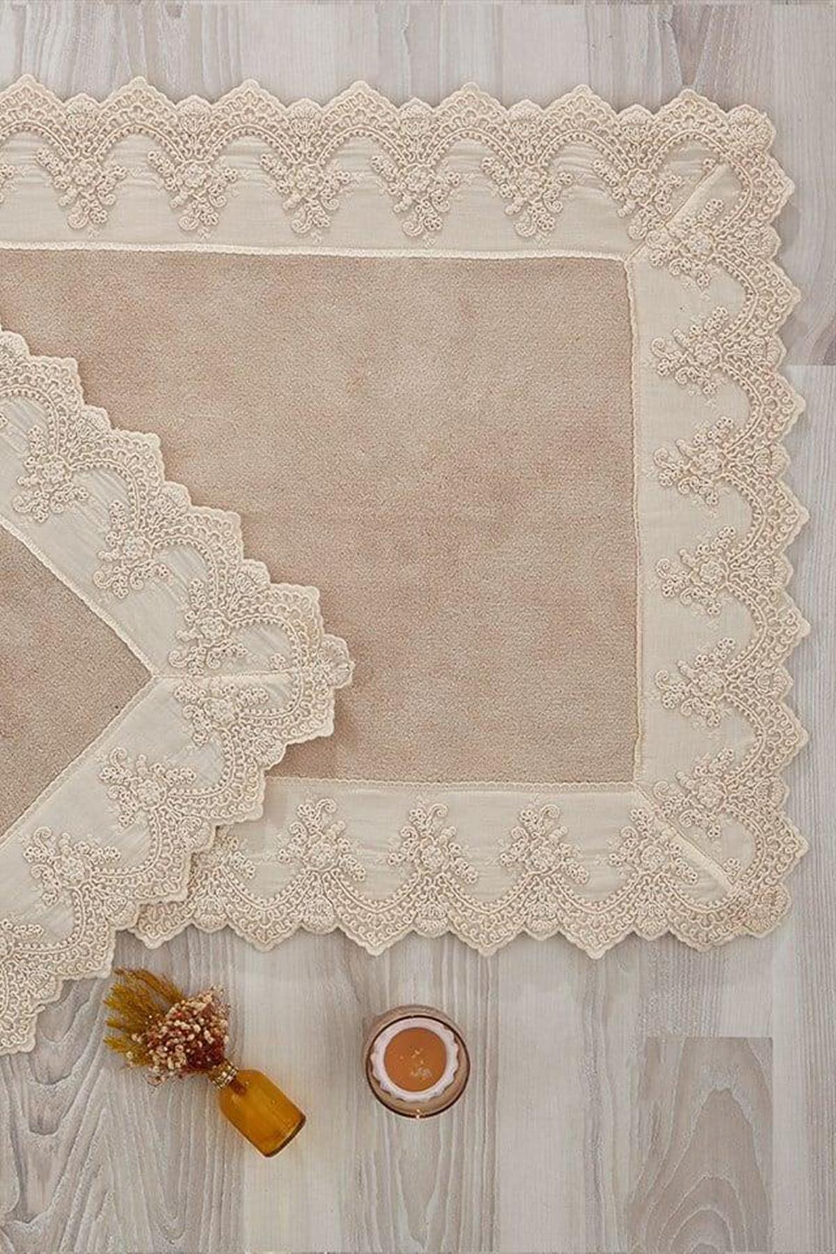 Set di 2 tappetini rettangolari color crema con ricami in pizzo, disposti in modo decorativo su un pavimento in legno